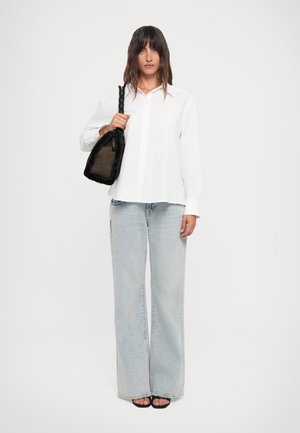 White button-up shirt, light blue wide-leg jeans, black bag with a textured surface, and black sandals. Smooth fabric and casual design.
