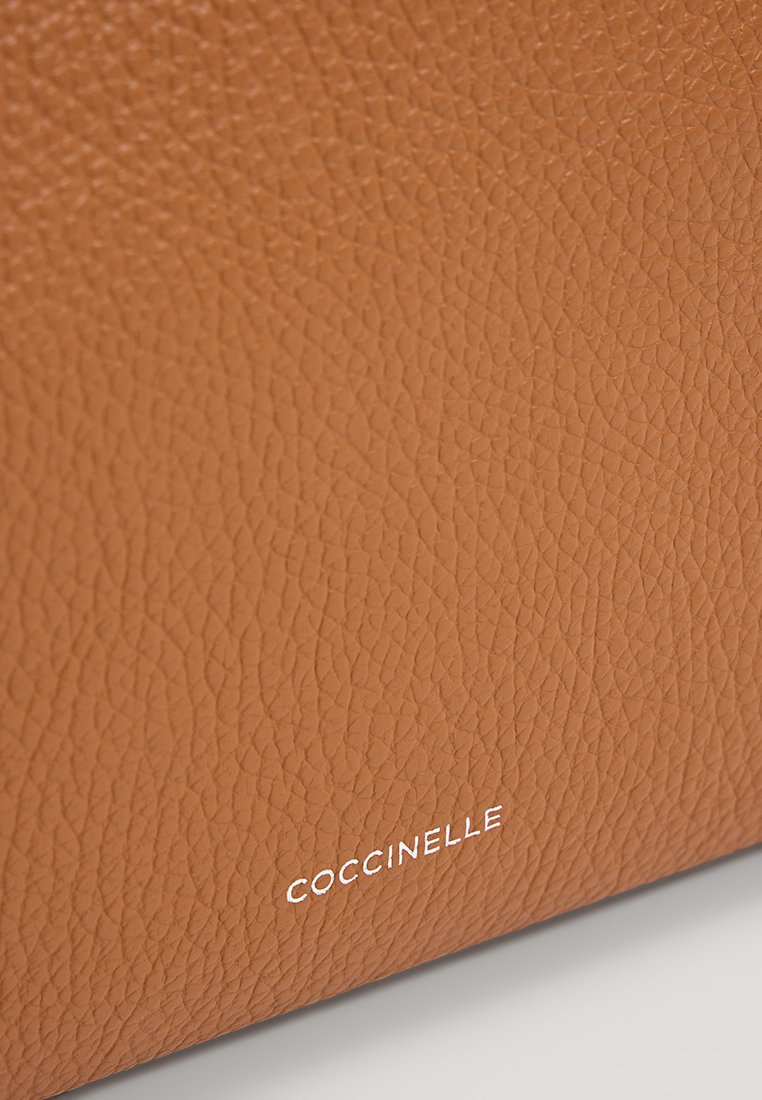 Brązowa torebka skórzana o teksturowanej powierzchni, z gładkim wykończeniem i subtelnym białym logotypem na dole.