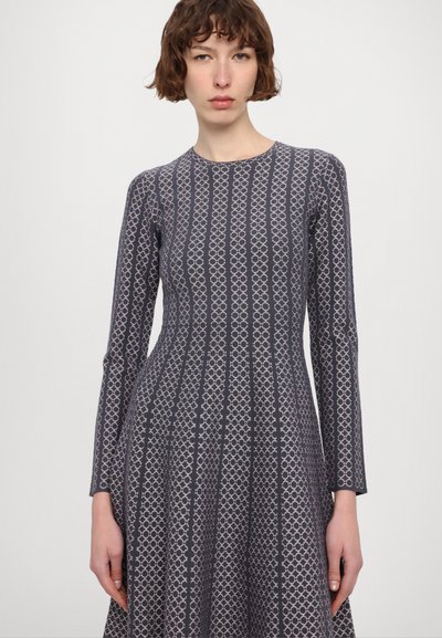 Abito a maniche lunghe di un blu navy scuro con motivi geometrici in rosa chiaro. Silhouette svasata, scollatura rotonda e tessuto strutturato.
