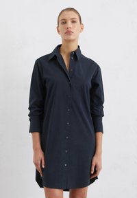 Sötétkék gombos ingruha gallérral, hosszú ujjal és egyenes szegéllyel, sima anyagból készült, minimalista dizájnnal.