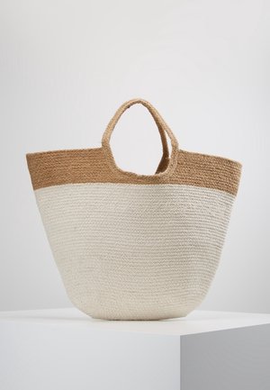 Two-tone woven tote bag in beige and light brown with short handles, displayed on a white pedestal against a plain background.