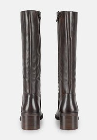 Bottes hautes en cuir brun avec une texture lisse, un talon courbé et un zip à l'arrière. Des coutures discrètes ajoutent du caractère au design.