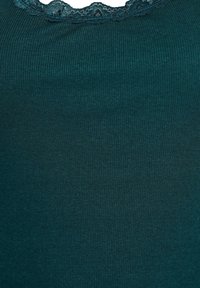 Tyrkysový rebrovaný top s vlnitým čipkovým výstrihom. Mäkkučký materiál, priliehajúci dizajn a jemný elastický efekt. Bez ďalších vzorov alebo akcentov.