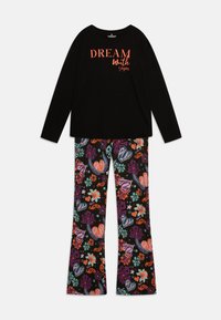 Black long-sleeve top with "DREAM with" text in orange, paired with patterned pajama pants featuring colorful shapes and floral designs on a black background.
