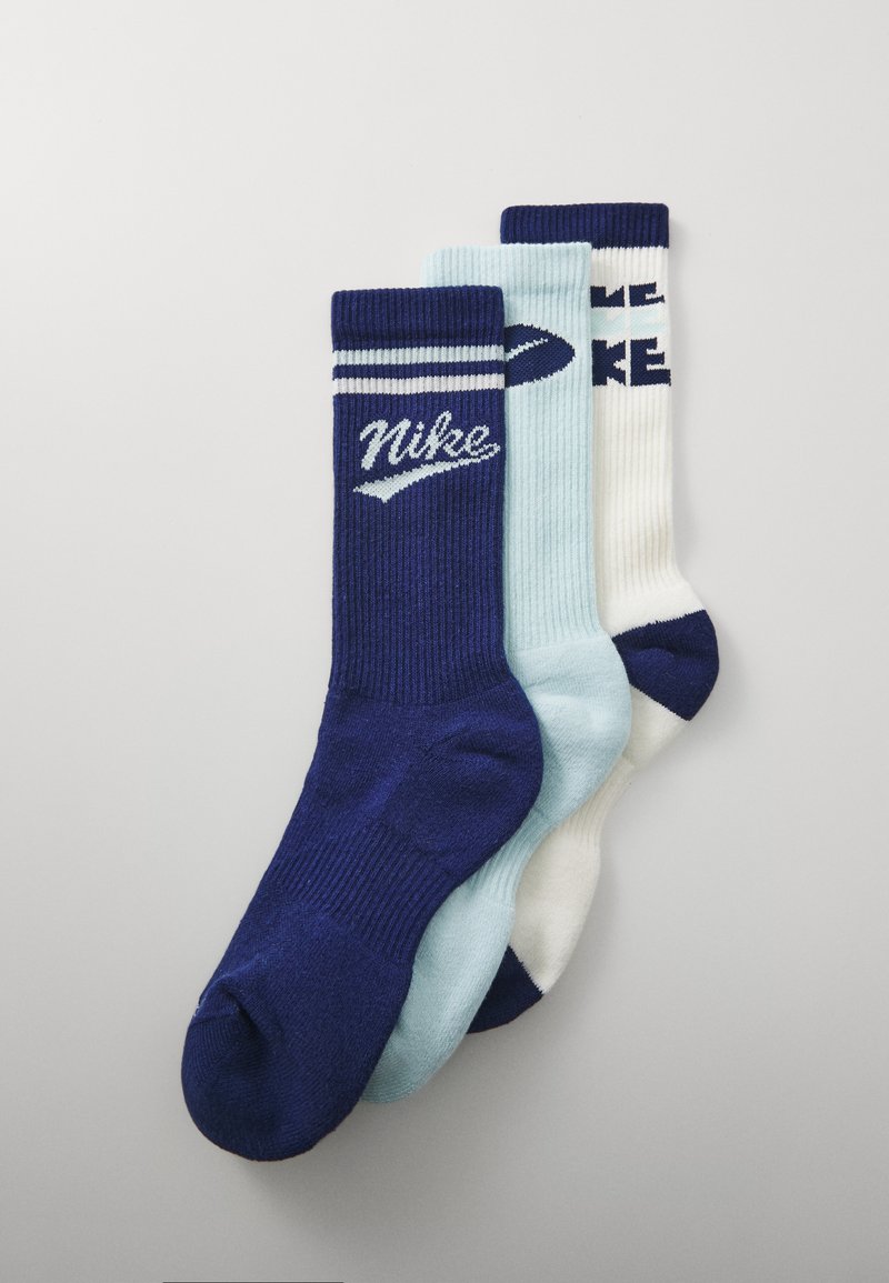 Trei perechi de șosete în nuanțe de albastru închis, albastru deschis și alb, prezentând texturi cu rigle și branding Nike în culori contrastante.