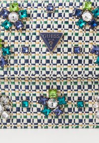 Borsa in tessuto intrecciato con un motivo blu, bianco e verde, decorata con gemme blu, verdi e trasparenti; accento in metallo con logo a forma di triangolo.