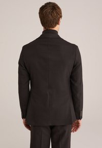 Schwarze maßgeschneiderte Sakkojacke aus leicht strukturiertem Stoff, mit einfachem Design und hohem Kragen. Verfügt über knöpfbare Manschetten und einen geraden Rücken.