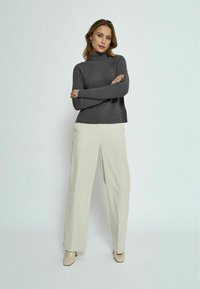 Gray ribbed turtleneck sweater paired with cream wide-leg trousers. The ensemble features a relaxed fit and smooth texture, accentuated by beige heels.