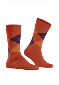 Chaussettes en coton orange avec un motif de diamants chevauchants en violet foncé et orange-jaune ; bord côtelé et texture lisse.