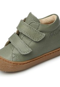 Scarpina verde in pelle per bambino con due fasce in Velcro, punta arrotondata, dettagli cuciti e suola in gomma marrone. Texture liscia, design semplice.