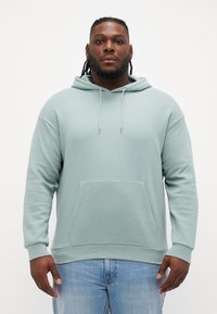 Lichtgroene hoodie gemaakt van zachte stof, met een voorkant zak, geribbelde boorden en een relaxte pasvorm.