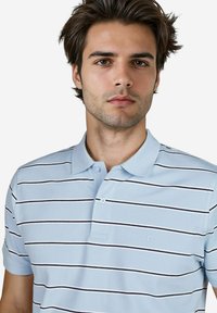 Lichtblauwe polo met horizontale marineblauwe en witte strepen, korte mouwen en een kraag met twee knopen. Bevat een subtiel logo op de borst.