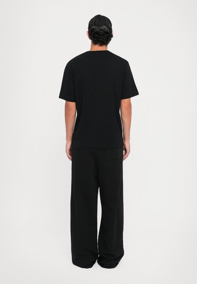 Black cotton t-shirt with short sleeves and a crew neck, paired with relaxed-fit, wide-leg black pants. Simple design, no visible logos or patterns.