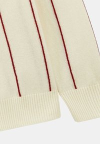 Pull crème avec des rayures rouges verticales, poignets et ourlet côtelés. Texture douce, présentant un design classique et un motif de tricot bien défini.