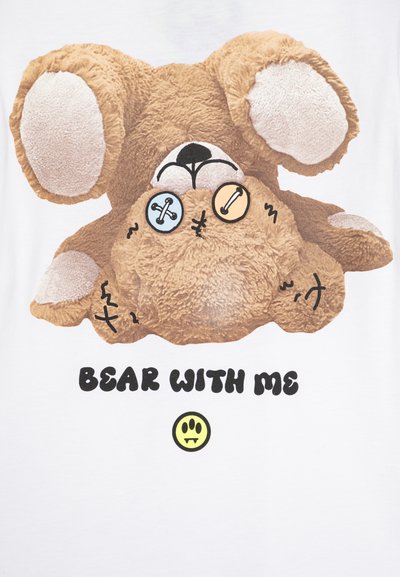 T-skjorte med et tegneserieaktig brunt kosedyrdesign med store ører, knappøyne og sydd detaljer, med teksten "BEAR WITH ME" under.