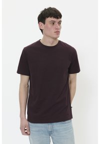 Camiseta de algodón burdeos de manga corta y cuello redondo, exhibida en un modelo sobre fondo blanco. Diseño simple en color sólido.
