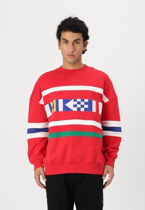 Punane dressipluus, millel on horisontaalsed triibud valge, sinise, kollase ja rohelise värviga ning geomeetriline muster ees. Puuvillane kangas, lõdva istuvusega.