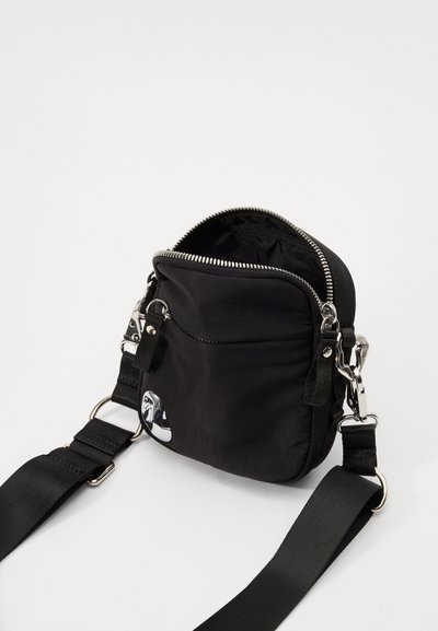 Geantă din nailon neagră, tip crossbody, cu un fermoar argintiu, un accent decorativ din crom și o curea ajustabilă lată. Partea de sus deschisă dezvăluie un interior moale.