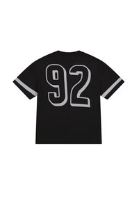 Camiseta negra de manga corta, con grandes números blancos '92' en la espalda. Las mangas tienen detalles de rayas blancas. Material de algodón.