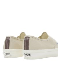 Sneakers beige in tela a basso profilo con cuciture di accentuazione marroni, suole in gomma bianche e un'etichetta con logo nero sul tallone.