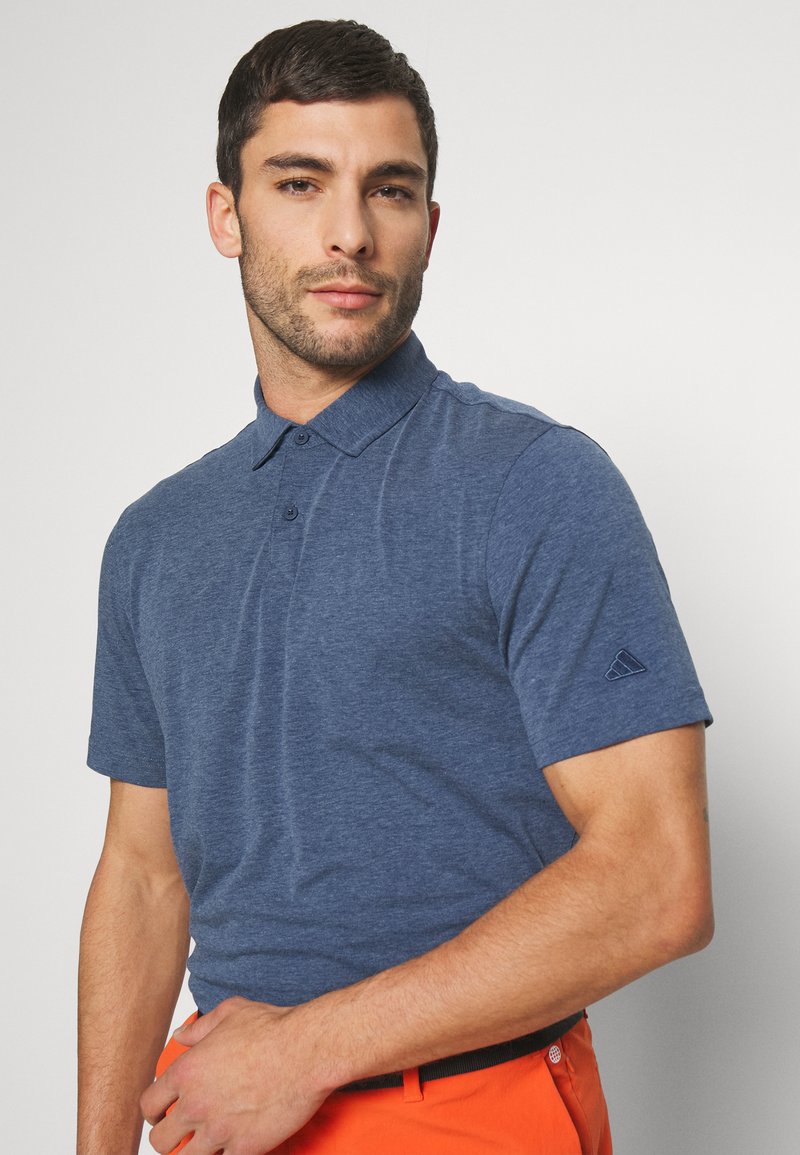 Polo de manga corta azul marino hecho de un tejido suave y texturizado; presenta un cuello tipo polo y dos botones en la parte delantera; logo sutil en la manga.