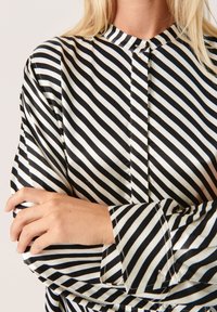 Zwart-wit gestreepte blouse met een mandarin collar, een soepele textuur en lange mouwen met knoopaccenten.