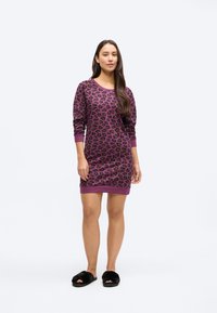 Obleka vijoličaste barve z leopardjim vzorcem, dolgimi rokavi, rebrastimi zaključki na manšetah in robu, izdelana iz mehke tkanine, kombinirana s črnimi puhastimi copati.