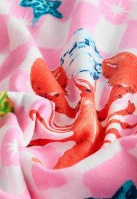Baumwollstoff mit rosa Hintergrund, der verspielte Muster von Meerestieren in Rot, Blau und Grün zeigt und eine weiche, strukturierte Oberfläche aufweist.