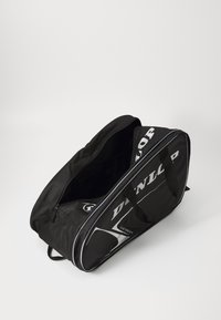 Borsa sportiva nera con chiusura a zip, manici e dettagli del logo bianchi. Presenta una forma arrotondata e un materiale testurizzato resistente.