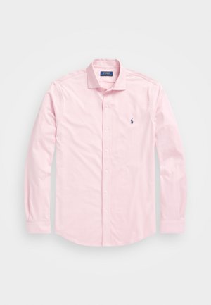 Gara piedurkne, pogām aizpogājama krekls gaiši rozā kokvilnā ar asu apkakli, kurai ir mazs tumši zilais polo logotips kreisajā krūtī.