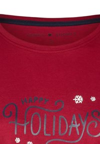 Rood katoenen T-shirt met de tekst "HAPPY HOLIDAYS" in blauw, met witte sneeuwvlokaccenten. Ronde halslijn met een contrasterende binnenband. Maat: S.