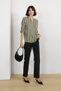 Olive green striped blouse with half sleeves and a placket, paired with black straight-leg pants and black slingback shoes. Holds a black bag.
