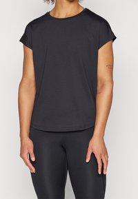 Czarny t-shirt sportowy z okrągłym dekoltem, krótkimi rękawami i luźnym krojem. Wykonany z materiału odprowadzającego wilgoć o gładkiej fakturze.