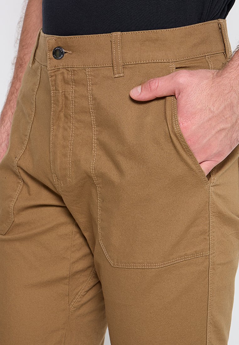 Pantalones de trabajo caqui con un corte recto, que cuentan con bolsillos delanteros, una tela resistente y costuras visibles. Color sólido con una textura suave.