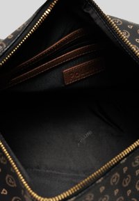 Interno di una borsa cosmetica marrone a motivo con fodera nera, scomparti con zip e un'etichetta in pelle marrone con il marchio "Pollini" impressa.