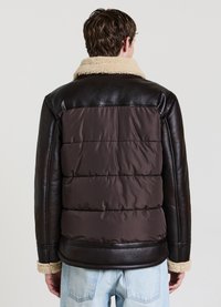 Veste en cuir marron avec un dos matelassé marron, col en mouton et poignets en polaire beige. Elle possède une texture matelassée et un ajustement structuré.