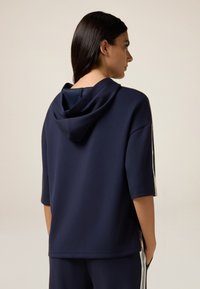 Sudadera con capucha azul marino de manga corta, con franjas laterales en blanco. Hecha de una tela suave y con un corte holgado.