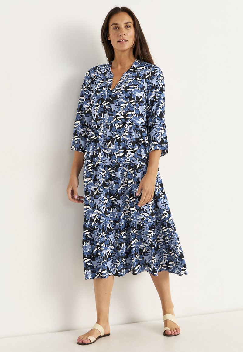 Blaues Blumenkleid mit drei Viertelärmeln, V-Ausschnitt, gestuftem Design und einer Mischung aus dunkelblau, hellblau, weiß und schwarz.
