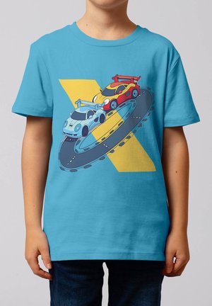 Kind trägt blaues Shirt mit Grafik von zwei Rennwagen, einem roten und einem hellblauen, die auf einer Schleifenstrecke gegen einen gelben X-Hintergrund fahren.