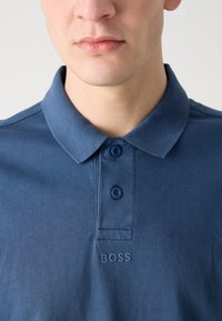 Σκούρο μπλε πόλο μπλούζα από βαμβάκι, με κολάρο, τριπλή κουμπότρυπα και υφασμένο λογότυπο "BOSS" στο στήθος.