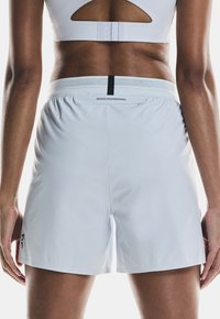 Vitaid shorts i vitt med perforerat mönster, elastisk midja med svart accent och en logotyp nere till vänster.