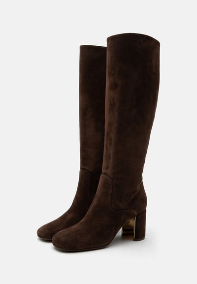 Bottes hautes en suède marron foncé à bouts arrondis et talons blocs avec un accent doré métallique sur le côté intérieur.