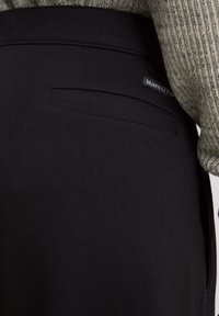 Pantalons noirs ajustés avec une finition texturée, dotés d'une poche arrière et d'une petite étiquette "Marc O'Polo" cousue dans la ceinture.