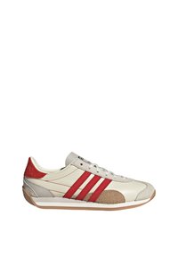 White sneaker featuring red stripes, tan accents, and a textured toe. Made from leather with a soft fabric heel and rubber sole.