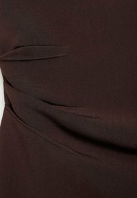 Tessuto marrone scuro con una superficie liscia, caratterizzato da pieghe e sottili dettagli drappeggiati, che creano un design strutturato.
