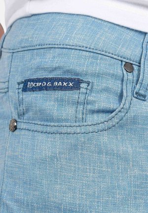 Lichtblauwe denim jeans met een opgestikte zak met geborduurd merklogo, zilveren metalen hardware en een gestructureerd stoffen detail.