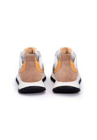 Sneaker con un tallone in suede beige e dettagli bianchi, arancioni e neri. Presentano una suola intermedia bianca imbottita e una suola esterna nera testurizzata.