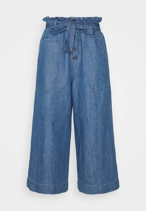 Culottes en denim taille haute, avec un lien en tissu ajustable, un bouton sur le devant et de grandes poches latérales. Couleur bleu clair avec une texture visible.