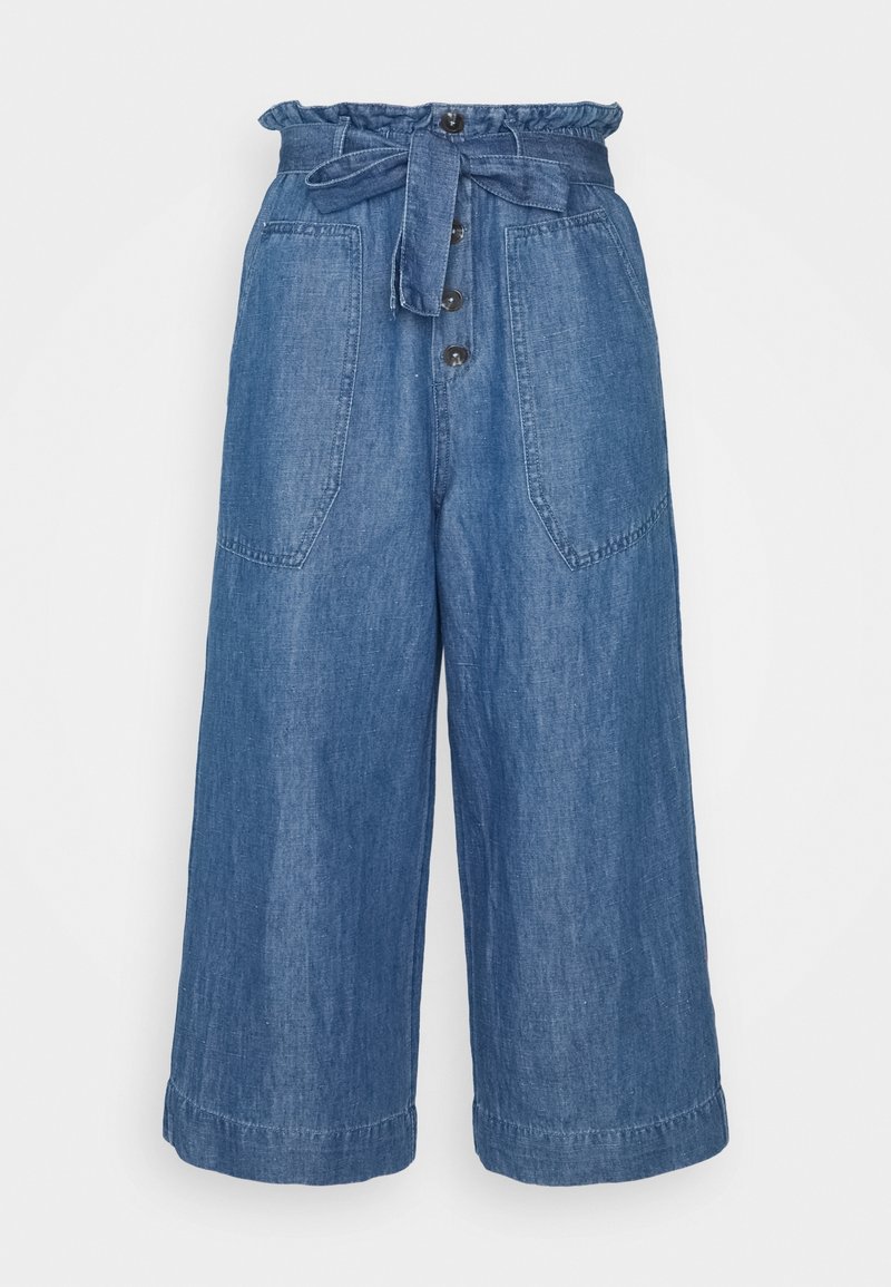 Culottes en denim taille haute, avec un lien en tissu ajustable, un bouton sur le devant et de grandes poches latérales. Couleur bleu clair avec une texture visible.