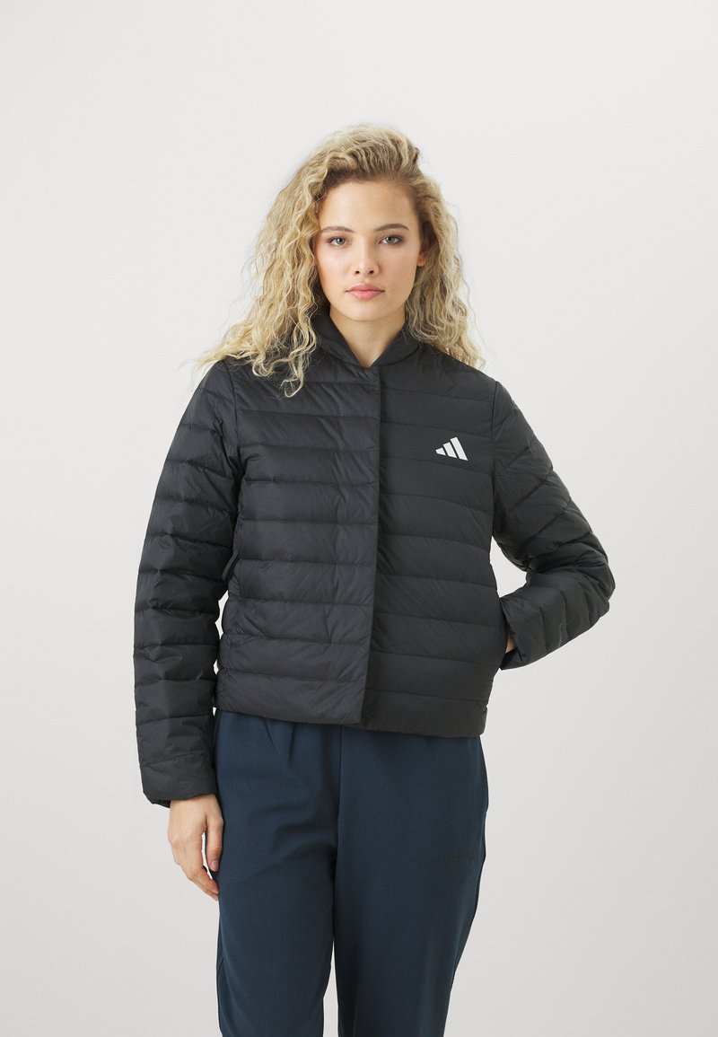 Crna puffer jakna s krojenjem do struka, horizontalno prošivenim dijelovima, visokim ovratnikom i bijelim Adidas logotipom na prsima.